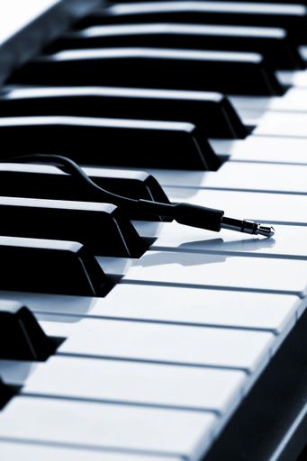 A closeup shot of the electric piano keyboard with a plug on the blurred background