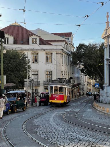 The number 28 tram in Lisbon passing through the city on a bright day