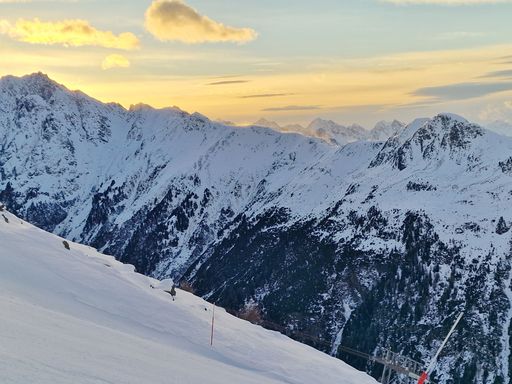 A snowy mountain range with a sunset sky in the background