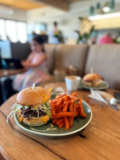 A vertical shot of burger sandwich and fries in green plate on wooden table in a restaurant