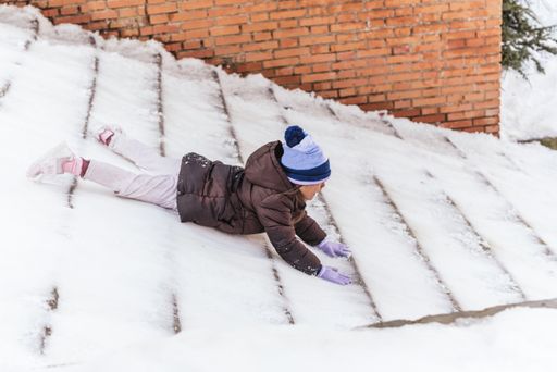 A shot of a little girl sliding in the snow like a sled