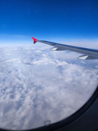 A vertical shot of the window view from an aircraft flying over a sea of clouds