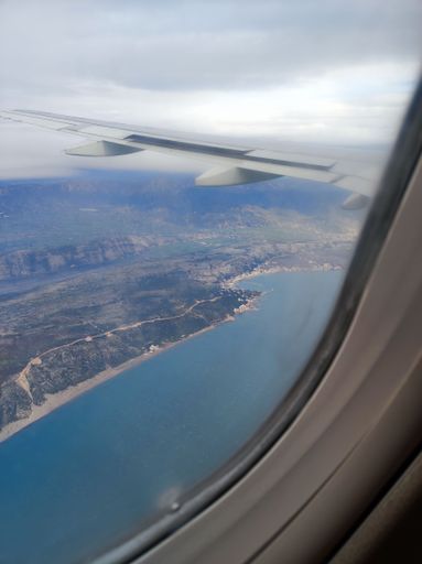 A vertical shot of the window view from an aircraft flying over an island