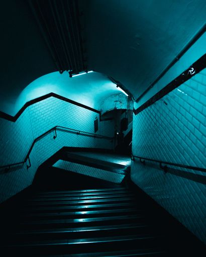 A beautiful vertical view of the underground stairs with blue lights on walls