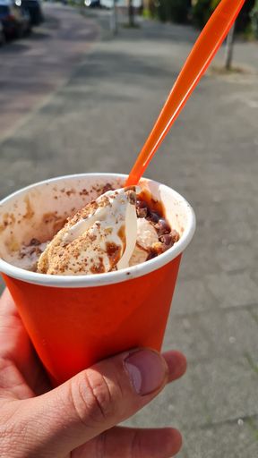 A vertical shot of the man holding the plastic cap of ice cream