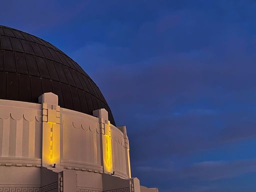 A low angle shot of Griffith Observatory against dark blue sky in twilight in Los Angeles, California