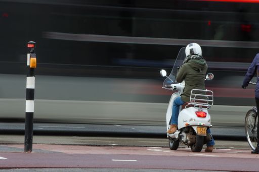 A street scene in Eindhoven featuring a bus and a woman on a scooter.