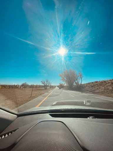 A vertical shot of a road and a vast landscape is seen from a car's side mirror