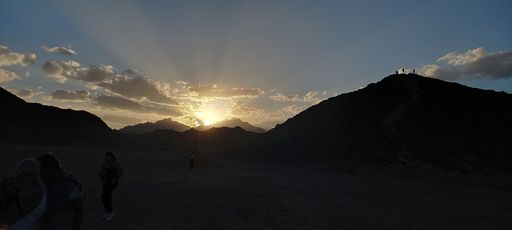 A panoramic shot of a beautiful sunrise over the silhouette of mountains.