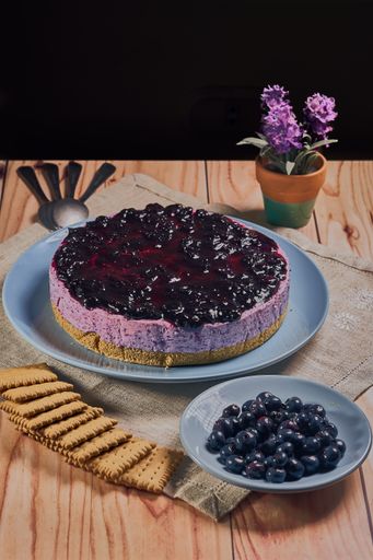 A vertical shot of a blueberry cheesecake on a wooden table