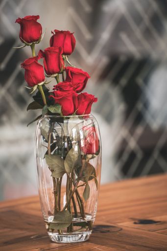 A vertical shot of a bunch of beautiful red roses in a glass vase on the table