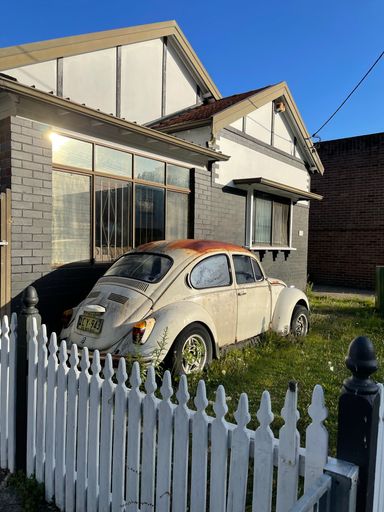A vertical shot of an old vintage car in the yard on a sunny day