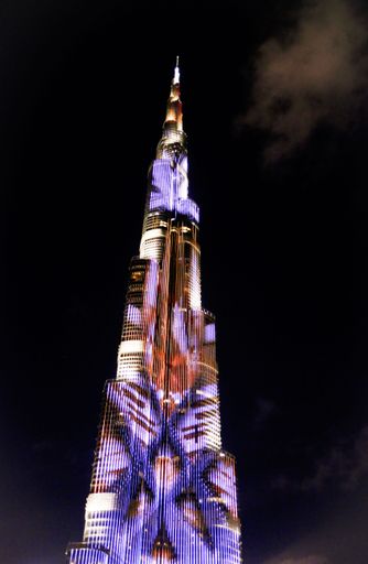 A vertical low angle shot of the illuminated Burj Khalifa building against the sky in Dubai at night