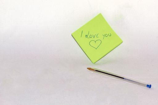 Note in which I love you is written by a lover on a small green sheet of paper with a blue pen.