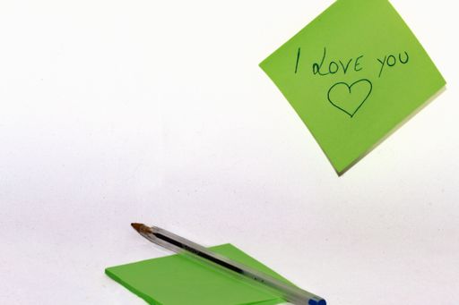 Note in which I love you is written by a lover on a small green sheet of paper with a blue pen.