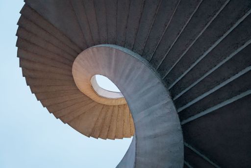 A low angle shot of curved spiral stairs under a bright blue sky
