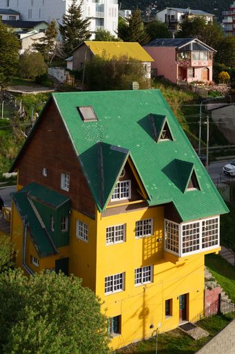 An aerial view of a colorful house in a residential neighborhood