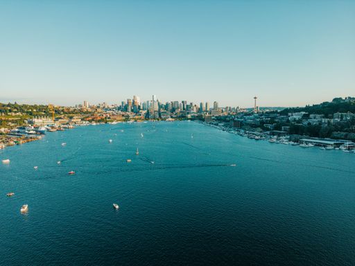 This is a drone shot of Seattle skyline in the back ground and Union Lake in the foreground