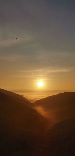 A vertical shot of a beautiful sunset seen from the peak of a mountain