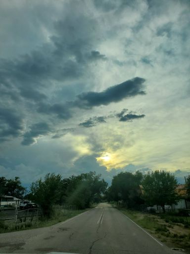 A Vertical shot of an empty asphalt road under blue cloudy sky