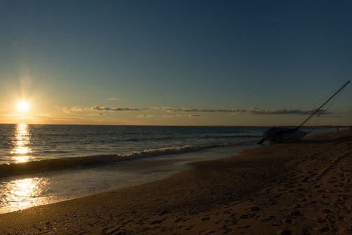 A small sailboat stranded on the beach at sunset in Punta Umbria, Spain
