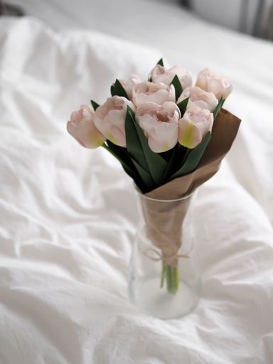 A vertical shot of a small pretty bouquet of white tulips in a vase in the bedroom