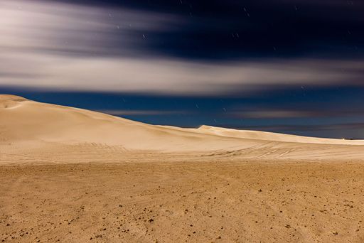 A landscape of sand dunes under a cloudy sky with long exposure at night in Lancelin, Australia