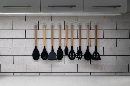 A closeup of a collection of silicon kitchenware hanging on a wall