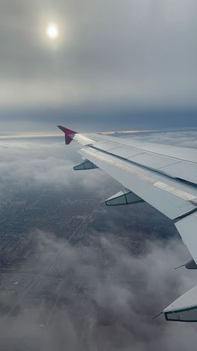 A vertical shot of one side of an airplane's wing on a foggy day from inside of the plane