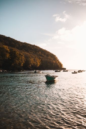 A vertical shot of a bright sunrise over the sea with boats
