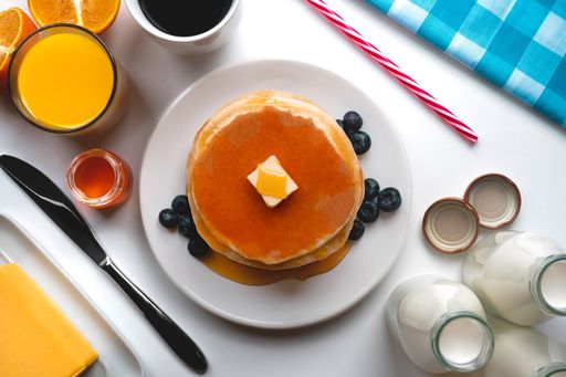 A top view of the pancakes served with butter and honey and a glass of orange juice