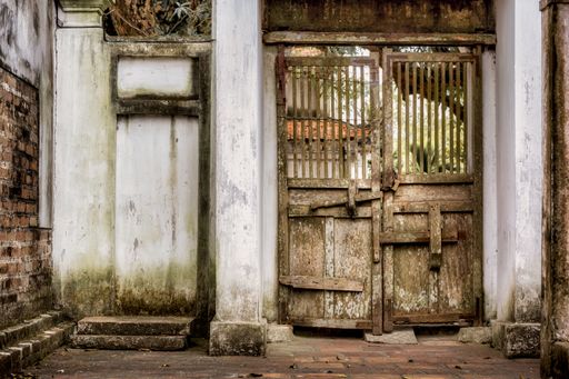 An ancient wooden gate in an old building with weathered walls
