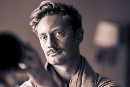A grayscale artistic self portrait of a beautiful male with a mustache posing in a mirror