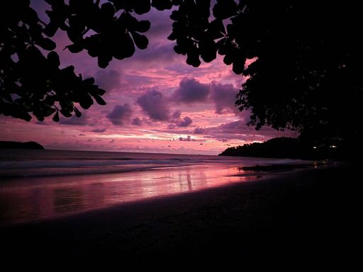 An aerial view of sea waves breaking beach during sunset