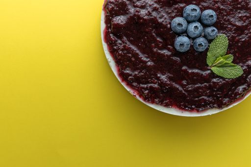 A top view of blueberry cheesecake with mint leaves isolated on yellow background