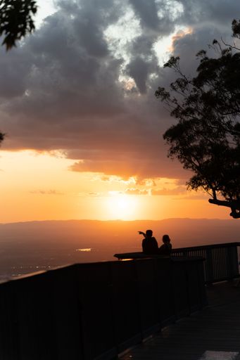 A vertical shot of a silhouette of people watching the sunset over a view