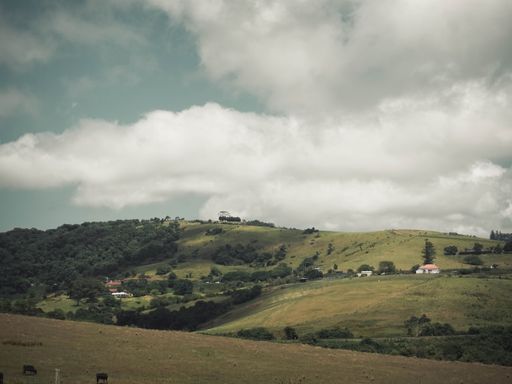 A beautiful landscape of hills with small houses and a herd of grazing cows under the blue cloudy sky
