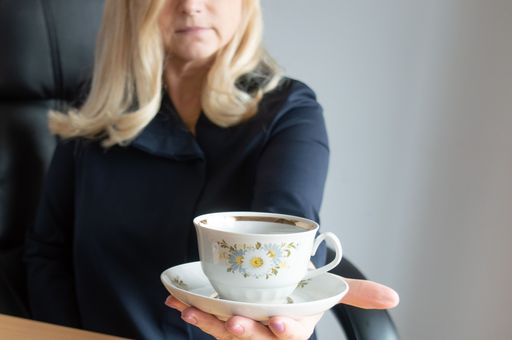 Woman holding a cup of coffee with a saucer. Selective focus on the cup