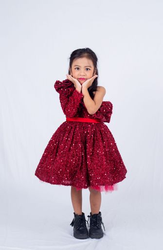 A little Asian girl in red dress posing in a studio.