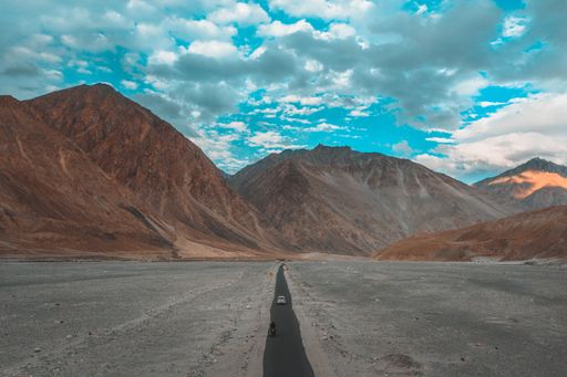 A scenic view of a long, paved road winding through the remote desert landscape, surrounded by rocky mountain ranges