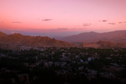 An aerial shot of a town with mountains on the background at red sunset