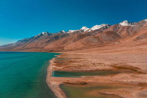 A scenic view of an empty coastline with turquoise water and mountain ranges under the cloudless sky