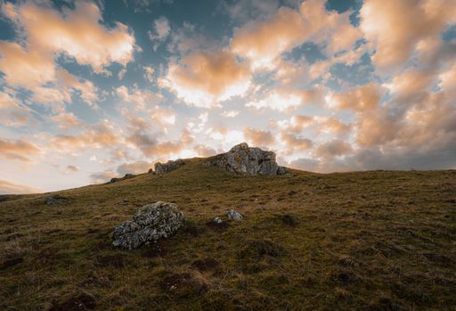 A beautiful shot of a cloudy sunset sky over a rural hill with stone formations in Baden-Wurttemberg
