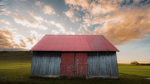 A beautiful shot of a cloudy sunset sky over a rural hill with a wooden barn in Baden-Wurttemberg