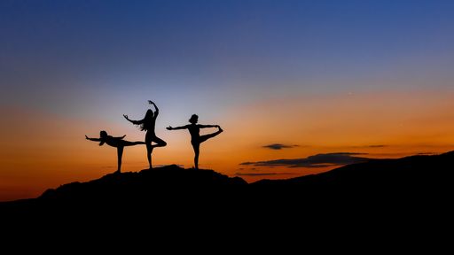A beautiful shot of a silhouette of people doing yoga on a mountain at sunset