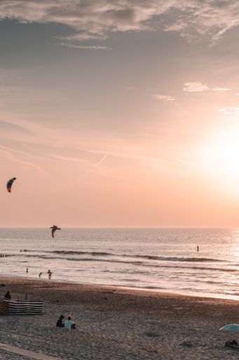 A vertical shot of the seascape at a stunning purple sunset, people resting on the beach