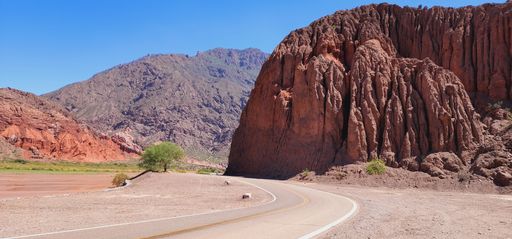 A scenic desert landscape featuring a winding road, leading to a majestic mountain range in the background