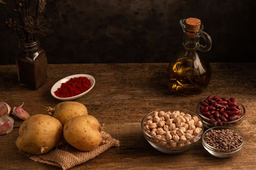 A low angle shot of potatoes, bowls of chickpea, red beans, lentil and other ingredients on table