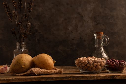 A shot of potatoes, tw bowls of chickpea, red beans and lentil and other ingredients on the table