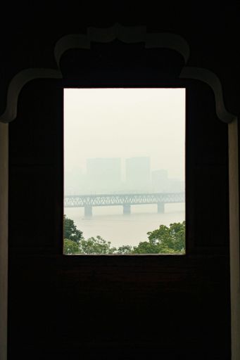 A bridge view from a window frame with dark around and foggy landmark background